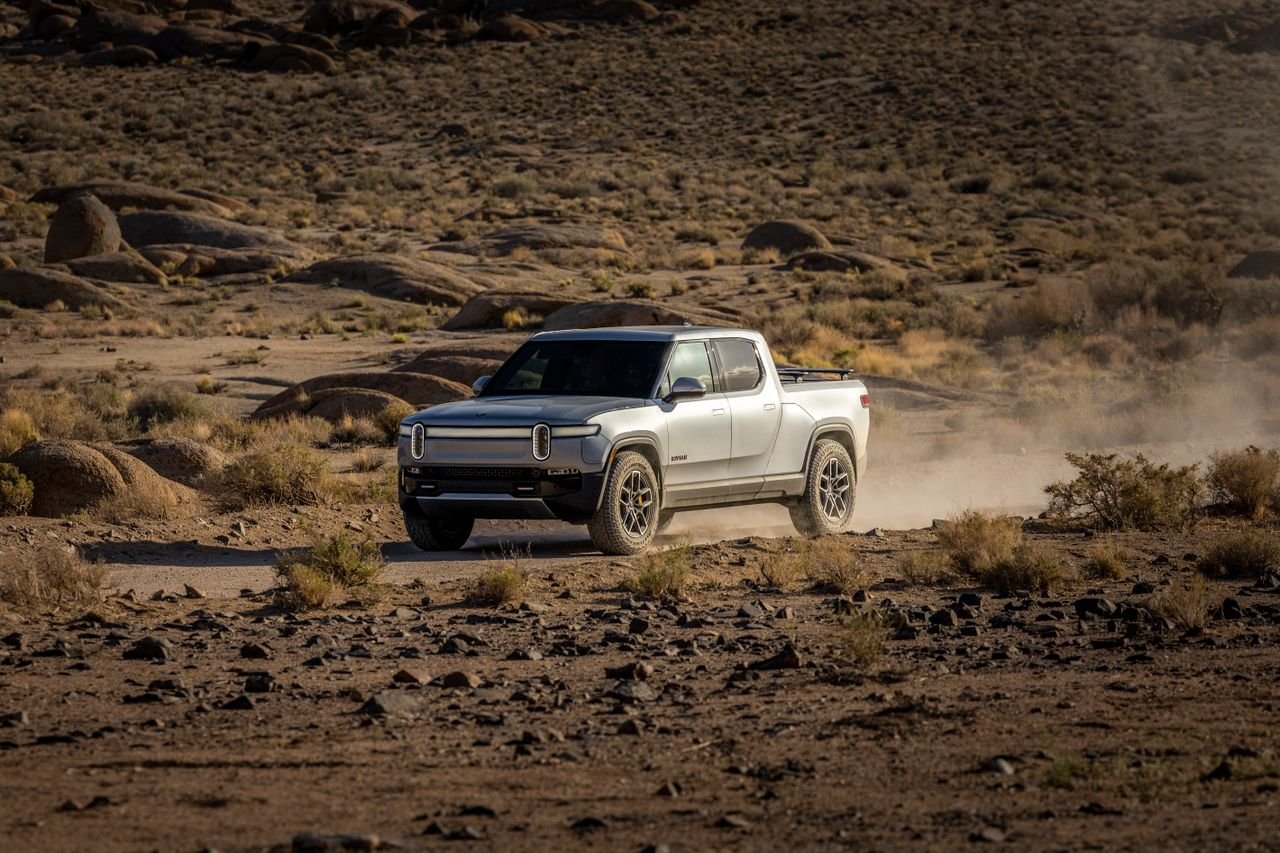 Rivian's R2 Finally Hits the Road: First Deliveries Begin at $45,000 Electric pickup truck navigating a rocky desert landscape, showcasing off-road capability and rugged terrain.